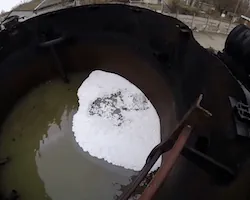 Inside a tank, Dryfoam beads introduced below the liquid rise and spread until they cover the surface